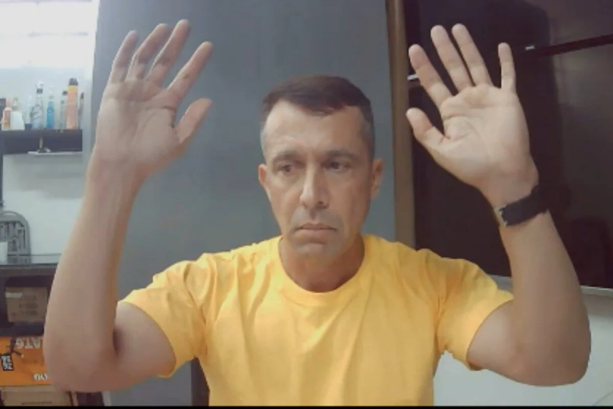 Homem branco cabelo curto, trajando camiseta amarela com ambas as mãos para o alto. Tenente-coronel Geraldo Leite Rosa Neto - Metrópoles