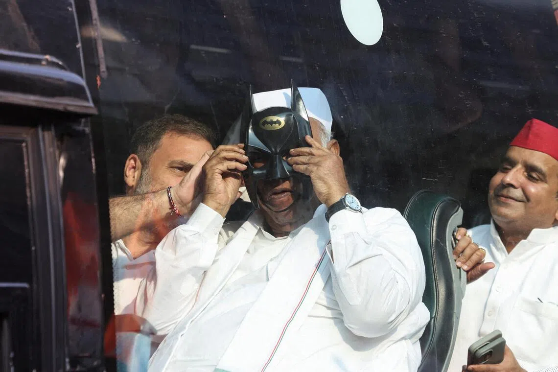 Congress party leader Rahul Gandhi helping party president Mallikarjun Kharge wear a Batman mask as opposition parties march to the Supreme Court in New Delhi on Oct 12 to protest a controversial revision of voter lists.