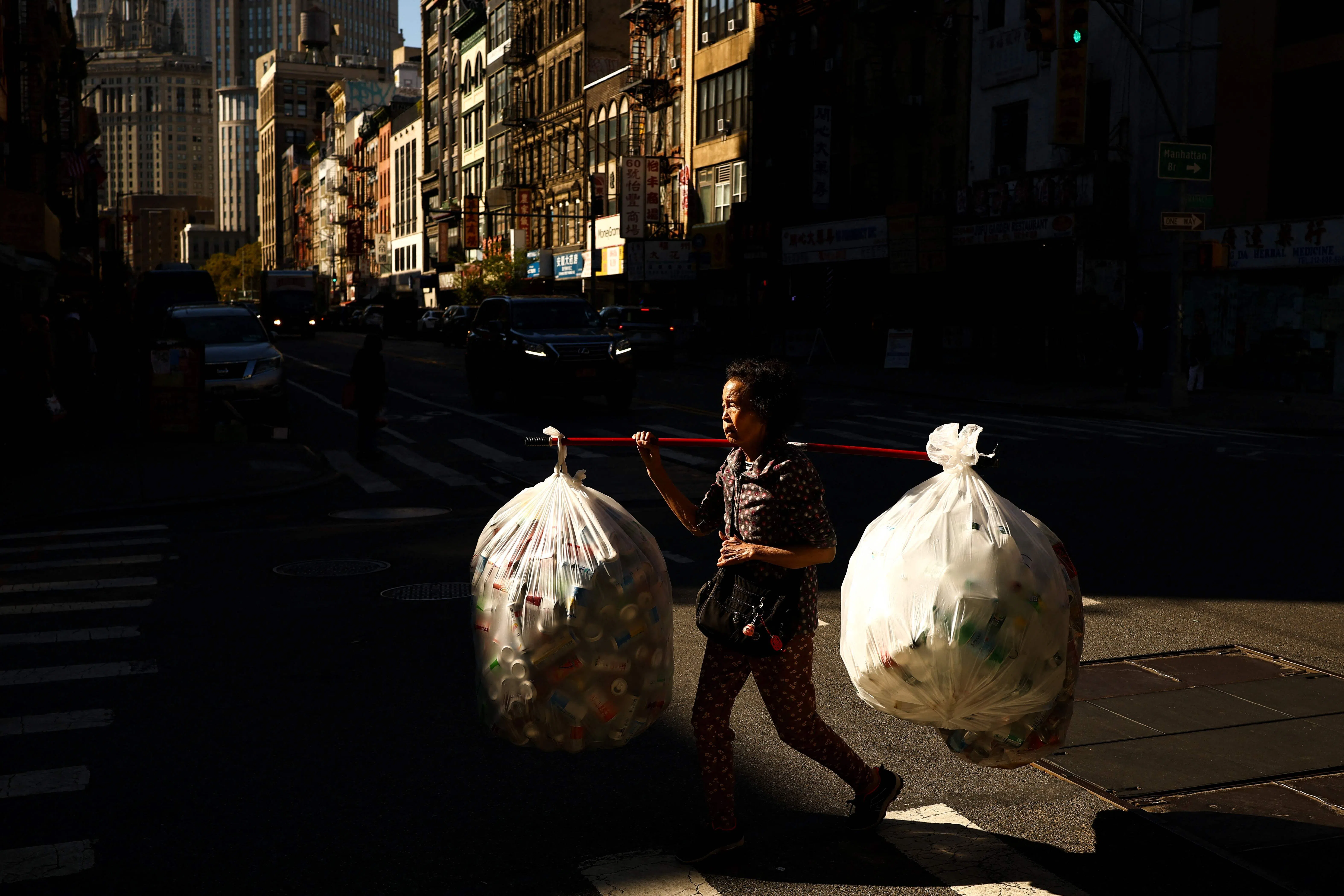 TOPSHOT - A woman carries bags of cans as she walks along a street in Chinatown in the Manhattan borough of New York, on October 20, 2026. (Photo by CHARLY TRIBALLEAU / AFP)