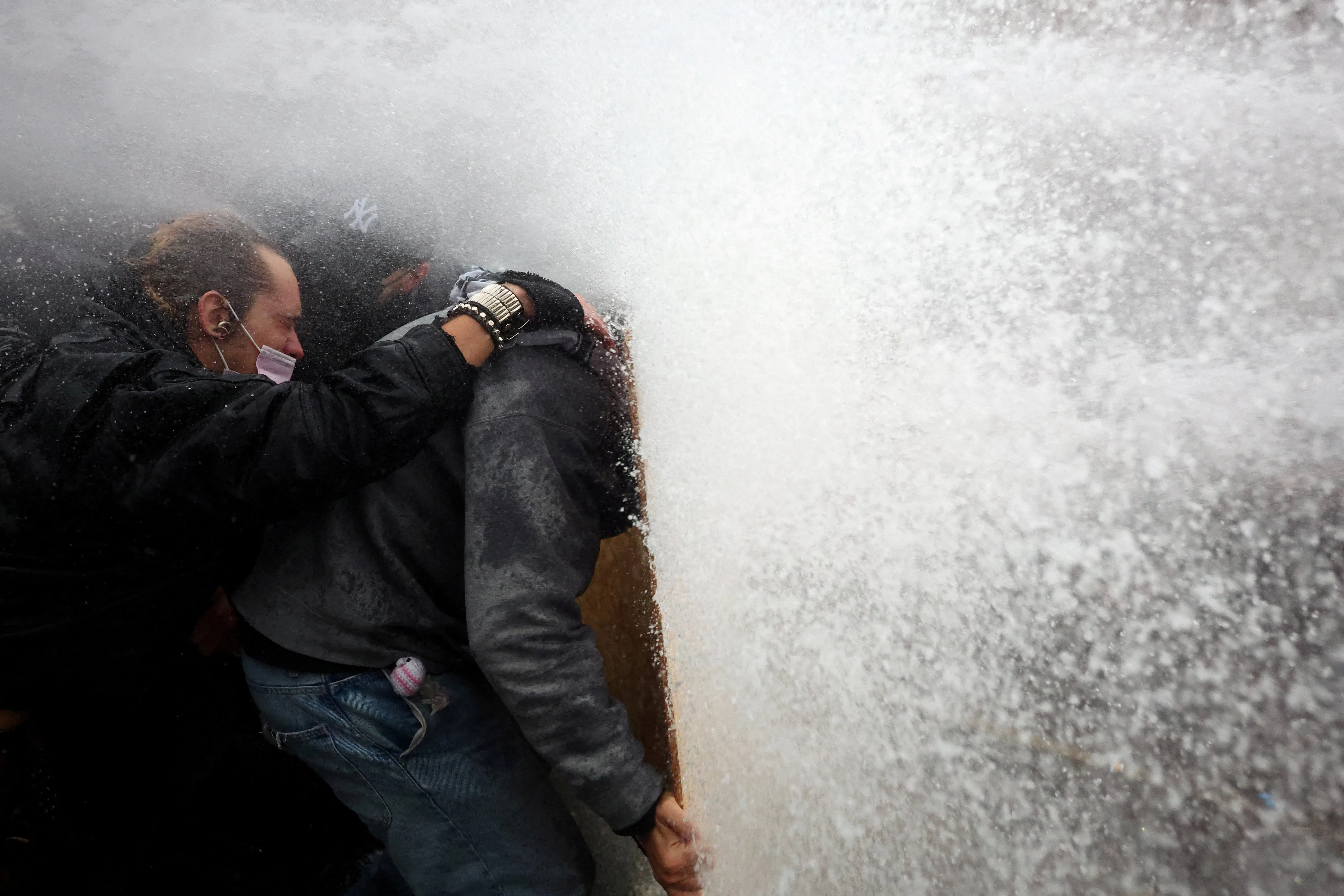 Protesters take cover behind a plywood board as French riot police use a water canon amid clashes during a demonstration organised by labour unions in Paris as part of nationwide protests called by the "Yellow Vests" movement joined by French high school and university students against the cost of living and rising fuel prices, in France, October 24, 2026. REUTERS/Pedro Nunes TPX IMAGES OF THE DAY